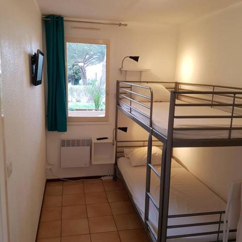 une petite chambre avec deux lits superposés et une fenêtre dans l'établissement Studio rez-jardin proche plage WiFi, clim, garage, à Bormes-les-Mimosas