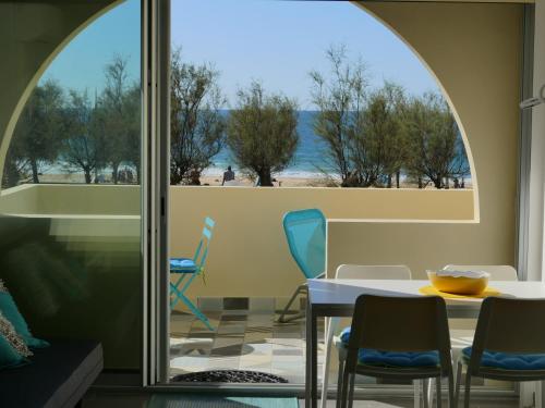 Cette chambre comprend une table et des chaises et offre une vue sur la plage. dans l'établissement La Dune d'Or - Vue Mer, Studio face à la Plage avec Terrasse, à Soorts-Hossegor