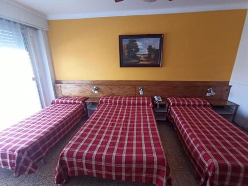 three beds in a room with a checkeredannelannel at HOTEL MILESI NECOCHEA in Necochea