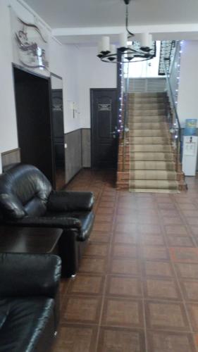 a lobby with a leather couch and stairs in a building at Ак-Тай Гостиный Двор in Ustʼ-Kamenogorsk