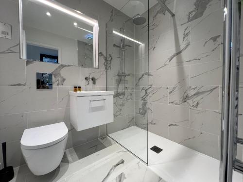 uma casa de banho branca com um WC e um chuveiro em South Street Apartments em Isleworth