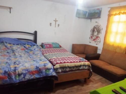 1 dormitorio con 1 cama, 1 silla y 1 cruz en la pared en Tequex, en Xochimancan