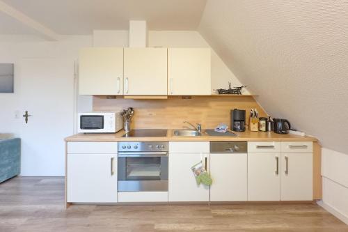 a kitchen with white cabinets and a sink at Up Süderdün 15 - Whg 1 in Norderney