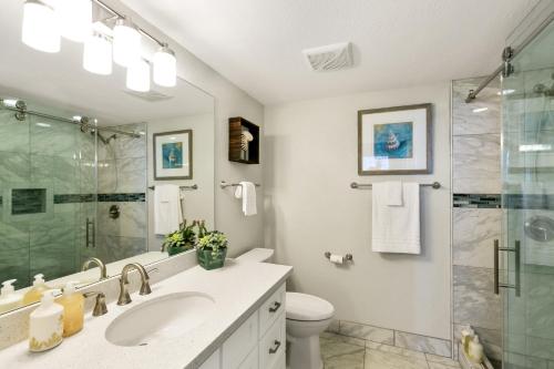 uma casa de banho com um lavatório e uma cabina de duche em vidro. em Renovated 2br Condo with Ocean Views - Alekona Kauai em Koloa