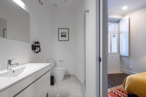 a bathroom with a sink and a toilet and a bed at Utopian Hotel, a charming guesthouse in Porto