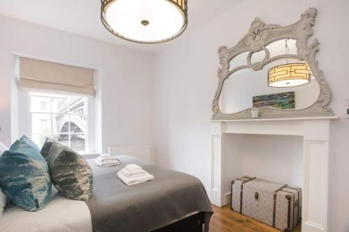 a bedroom with a bed with a mirror and a suitcase at Historic House On The Bridge in Bath