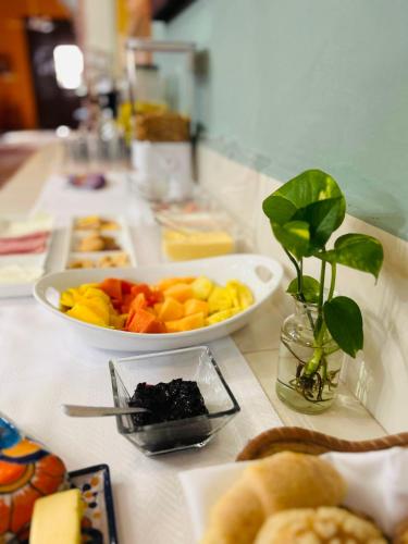 a table with a bowl of fruit and a plate of bread at Casa Tres Colibries in Mérida