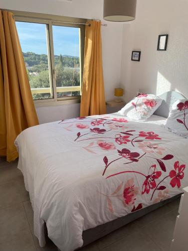 - une chambre avec un lit doté d'un couvre-lit floral et d'une fenêtre dans l'établissement T2 Saint-Mandrier-sur-Mer, à Saint-Mandrier-sur-Mer
