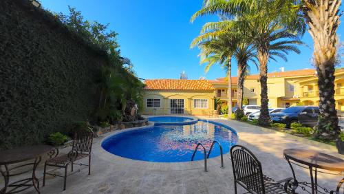 a swimming pool in front of a house with palm trees at Hotel Florencia in San Miguel