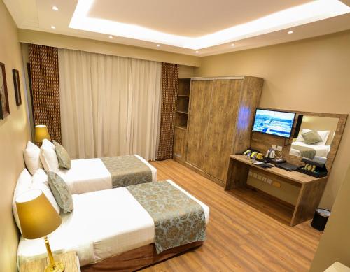a hotel room with two beds and a television at Al Ansar Golden Tulip in Al Madinah
