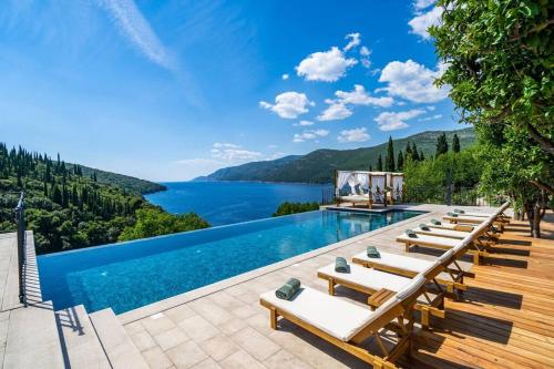 a pool with lounge chairs and a view of a lake at Peaceful Villa Palma with a pool in Dubrovnik in Gruda