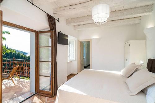 a bedroom with a white bed and a balcony at Peaceful Villa Palma with a pool in Dubrovnik in Gruda