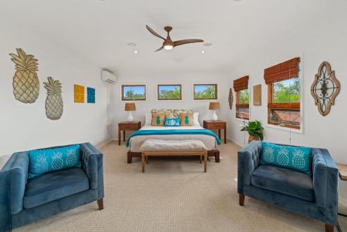 a bedroom with a bed and two blue chairs at Custom 4br Home Walking Distance to Beach - Alekona Kauai in Koloa