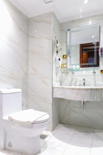 a white bathroom with a toilet and a sink at Al Ansar Golden Tulip in Medina