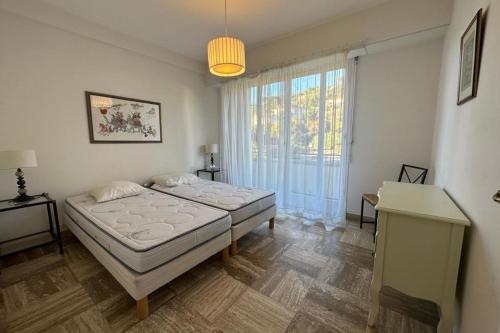 une chambre avec deux lits et une grande fenêtre dans l'établissement WE CANNES ! Amazing Sea View 2 Bedrooms La Vista, à Cannes