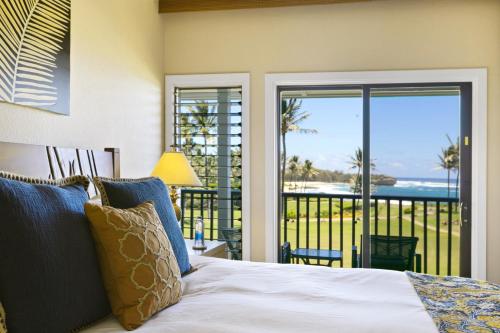 a bedroom with a bed and a view of the ocean at Prime Oceanfront Condo near Shipwreck Beach - Alekona Kauai in Koloa
