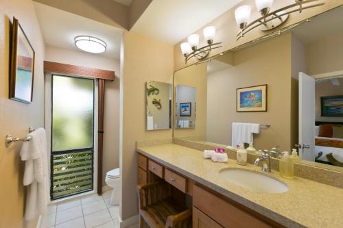 a bathroom with a sink and a toilet and a mirror at Prime Oceanfront Condo near Shipwreck Beach - Alekona Kauai in Koloa