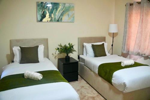 a bedroom with two beds and a lamp at Luxury Home near NEC, BHX with Parking and Netflix in Solihull