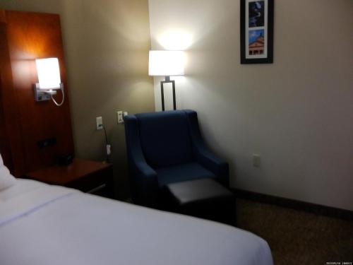a hotel room with a bed and a blue chair at Wingate by Wyndham Buckhannon in Buckhannon