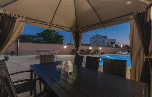 a table and chairs under an umbrella next to a pool at Elegant Villa Jure with private pool in Poličnik
