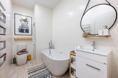 ein Badezimmer mit einer Badewanne, einem Waschbecken und einem Spiegel in der Unterkunft Seabreeze Retreat with terrace - St Julians in St Julian's