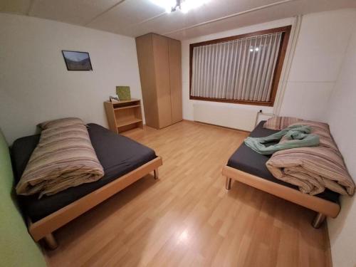 um quarto com 2 camas e piso em madeira em Ferienwohnung Brüstiblick em Attinghausen