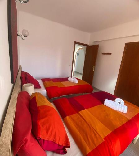 two beds in a room with red and orange sheets at Rotonda Apartaments in Felanitx