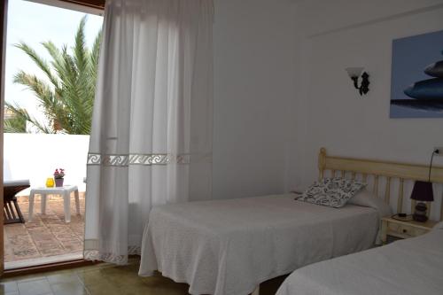 a bedroom with two beds and a window with a patio at Rotonda Apartaments in Felanitx