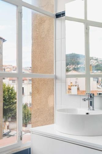 une salle de bain blanche avec un lavabo et une fenêtre dans l'établissement Regina's Banyuls - Exklusiv lägenhet med havsvy, à Banyuls-sur-Mer