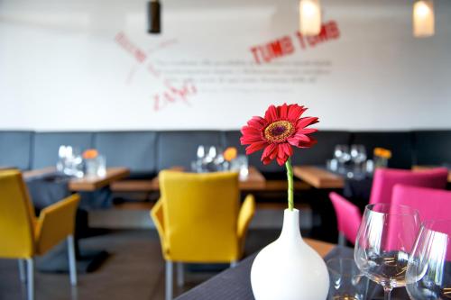 a red flower in a white vase on a table at Mercure Nerocubo Rovereto in Rovereto