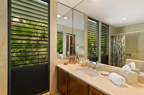 La salle de bains est pourvue d'un lavabo et d'un grand miroir. dans l'établissement Oceanfront Corner Villa w Air Conditioning - Alekona Kauai, à Koloa
