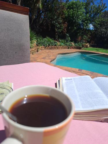 a cup of coffee sitting on a table with a book and a book at La Château B&B in Springs