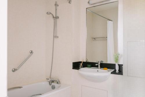 a white bathroom with a sink and a bath tub at Sonder Kensington Gardens in London