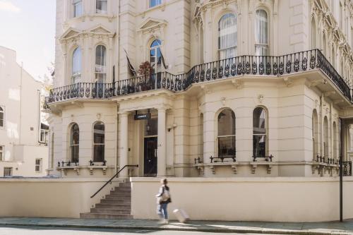 a woman walking in front of a building at Sonder Kensington Gardens in London