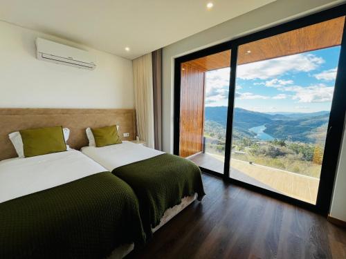 a bedroom with two beds and a large window at Encosta do Gerês Village in Braga