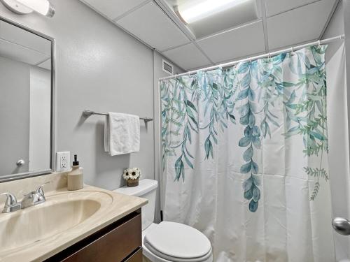 a bathroom with a shower curtain with a toilet and a sink at Downtown 1br Gem Steps Away From Wells Fargo in Des Moines