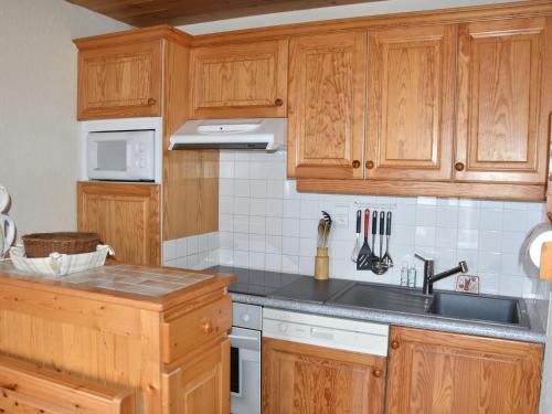 une cuisine avec des armoires en bois et un évier dans l'établissement Appartement spacieux proche télécabine avec terrasse et WiFi - FR-1-464-51, à Champagny-en-Vanoise