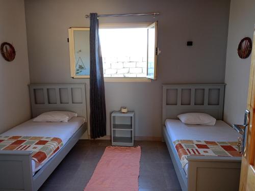 two beds in a room with a window at Studio with a spacious garden in Al-Assla in Dahab