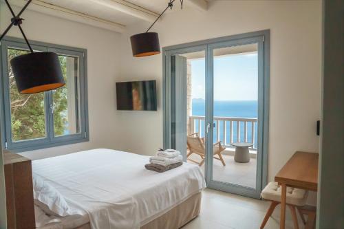 a bedroom with a bed and a balcony with the ocean at Urania Luxury Villa Rhea in Póndi