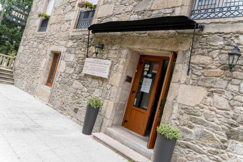 a stone building with a door and a sign on it at Hotel A Casa Do Rio in Padrón