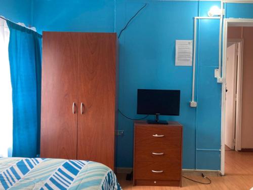 Dormitorio con cama y tocador con TV en hospedaje 12 de octubre, en Coyhaique