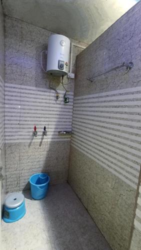 a bathroom with a shower with a toilet and a bucket at Laxmi Dormitory in Vrindāvan