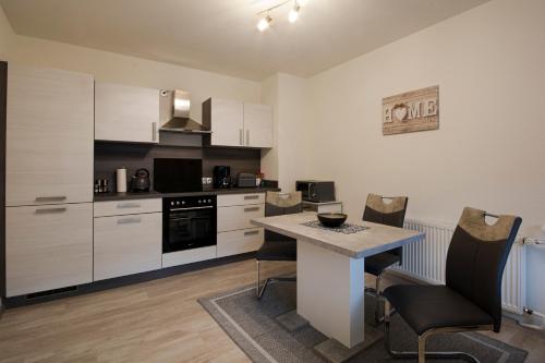 a kitchen with white cabinets and a table and chairs at Ferien Wohnung Weinheim - Die FeWo i.d. Nordstadt in Weinheim