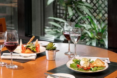 a table with two plates of food and wine glasses at Meliá Paulista in Sao Paulo