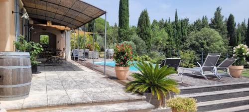 een patio met stoelen, een zwembad en bomen bij Le Petit Mas Rouge in Saint-Rémy-de-Provence