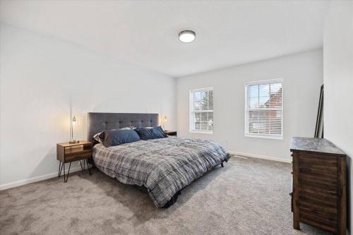 a bedroom with a bed and a dresser and two windows at Centrally located renovated home in Columbus