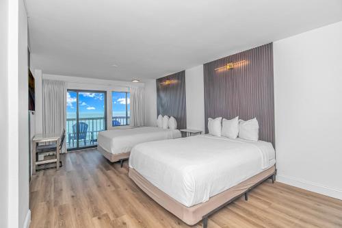a hotel room with two beds and a balcony at Grande Beach Resort in Myrtle Beach