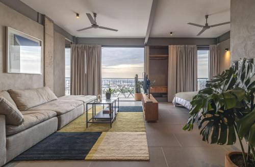 a living room with a couch and a large window at Departamentos y Suites Índigo in Querétaro