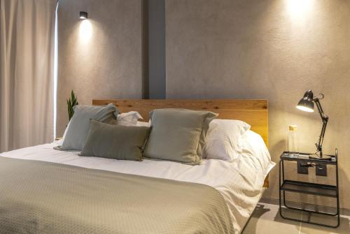 a bedroom with a bed with white sheets and pillows at Departamentos y Suites Índigo in Querétaro