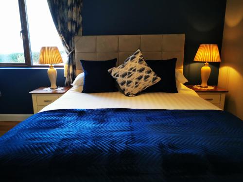 a bedroom with a blue and white bed with two lamps at Ocean Heights B&B in Lissadell